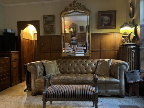 Élégant salon avec canapé Chesterfield en cuir gris, miroir doré ornementé et boiseries à l'hôtel Maison 1850 Paris