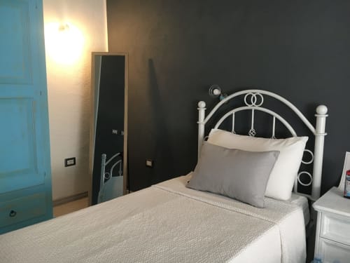 Camera moderna all'Agriturismo Il Pomo d'oro con letto in metallo, cuscini bianchi, biancheria grigia e porta turchese
