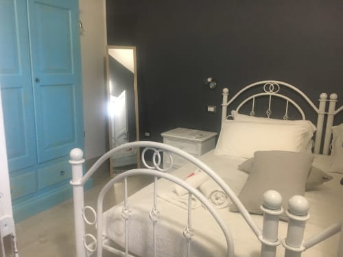 Camera moderna con letto in metallo bianco presso Agriturismo Il Pomo d'oro ad Assemini, con parete accent scura e turchese