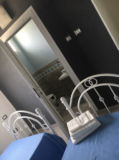 Camera moderna con letti in metallo e biancheria bianca presso l'Agriturismo Il Pomo d'oro ad Assemini, Italia