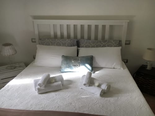 Spaziosa camera da letto presso l'agriturismo Il Pomo d'oro con letto bianco, asciugamani arrotolati e vista sul giardino ad Assemini, Italia