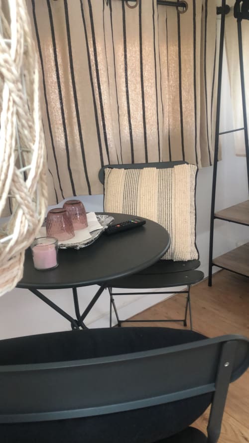 Accogliente angolo relax all'Agriturismo Il Pomo d'oro con sedie in metallo nero, tende righe, cuscino crema, candele rosa