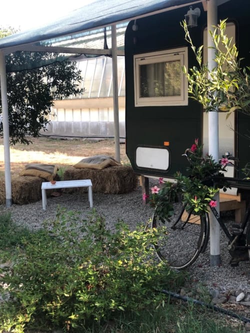 Elegante glamping trailer nero con fiori presso l'Agriturismo Il Pomo d'oro ad Assemini, Italia, con zona salotto e giardino
