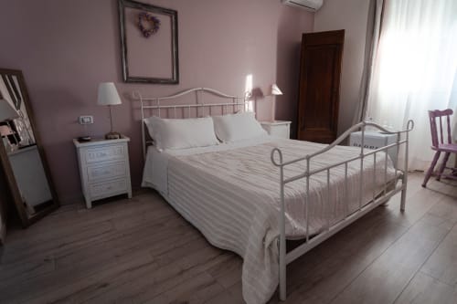 Camera Lavanda presso l'Agriturismo Il Pomo d'oro di Assemini con letto in ferro, biancheria bianca e vista sul giardino.
