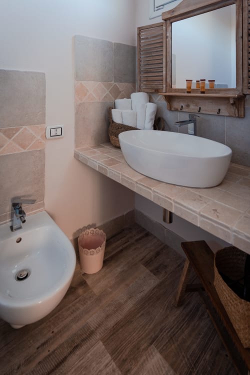 Bagno moderno nella Stanza Lavanda di Agriturismo Il Pomo d'oro con lavabo ovale bianco, piastrelle in pietra e specchio con cornice in legno
