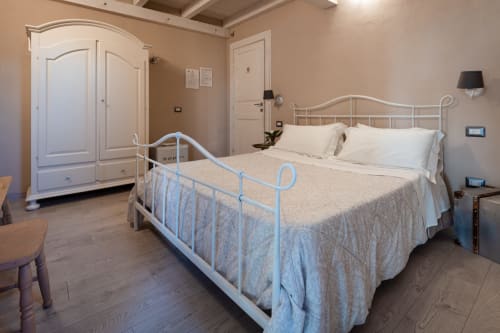 Elegante camera da letto in Agriturismo Il Pomo d'oro ad Assemini con letto in ferro, guardaroba bianco e vista sul giardino