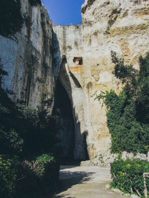 Antico passaggio nella fortezza in pietra di Siracusa con muri consumati dal tempo e vegetazione verde