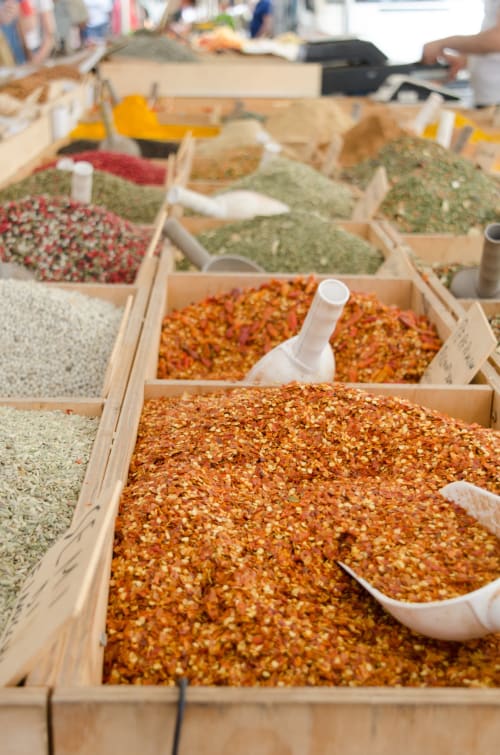 Esposizione del mercato delle spezie a Casa Epicarmo Siracusa con erbe aromatiche, spezie e condimenti colorati in scatole di legno