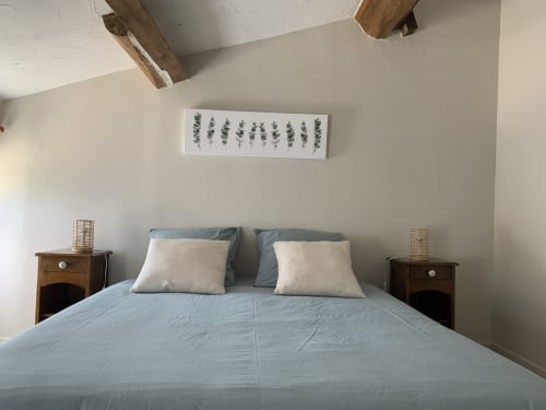 Lit double confortable avec draps verts dans la chambre d'hôtes Le Marais à La Chabanaise, ambiance douce sous les poutres apparentes et décoration végétale chaleureuse.