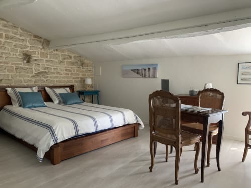 Chambre Océane de la maison d'hôtes La Chabanaise avec un grand lit double, un mur en pierre apparente, un coin bureau en bois et un plateau de courtoisie avec bouilloire électrique.