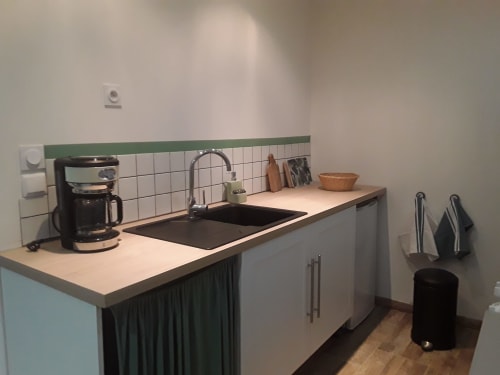 Pequeña cocina moderna en la casita Château De Clusors con fregadero, cafetera y azulejos blancos de pared
