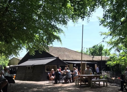 Three Little Pigs farmyard outdoor dining area with black barn buildings and rustic tables in Blandford Forum