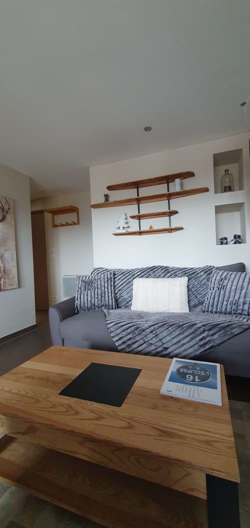 Salon moderne de la Résidence Le Pacha à Courchevel avec canapé gris, étagères en bois et table basse en bois