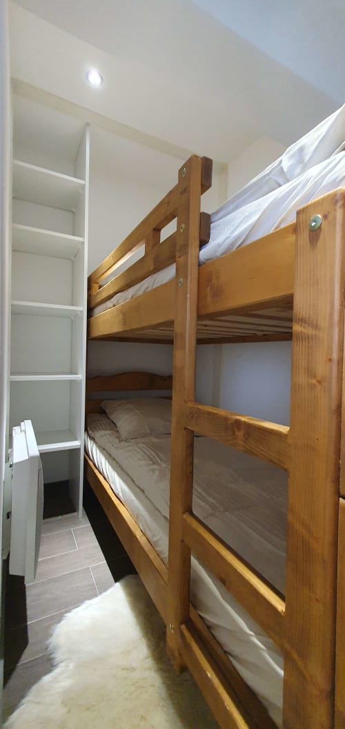 Lit superposé en bois avec literie blanche dans un confortable appartement de Courchevel à la Résidence Le Pacha, avec rangements et vue sur les montagnes