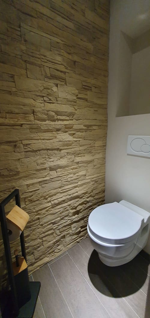 Salle de bains moderne à la Résidence Le Pacha, Courchevel avec mur en pierre texturée et toilettes contemporaines blanches