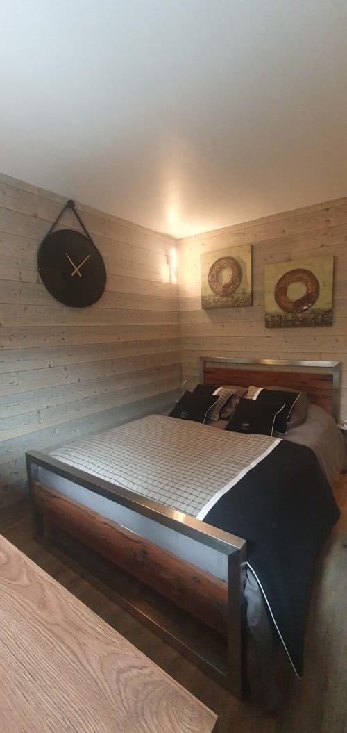 Chambre douillette à la Résidence Le Pacha, Courchevel avec murs en bois, lit, horloge noire et art mural circulaire rustique