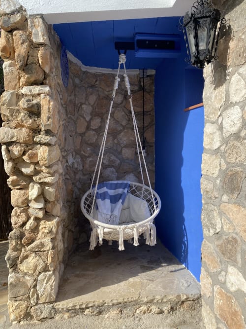 Silla colgante de macramé en nicho azul en BondBeach Village, Altafulla