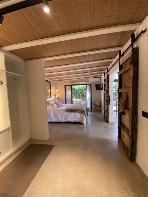 Moderno dormitorio en BondBeach Village en Altafulla con vigas de madera en el techo, pisos de hormigón y puertas de vidrio que se abren a