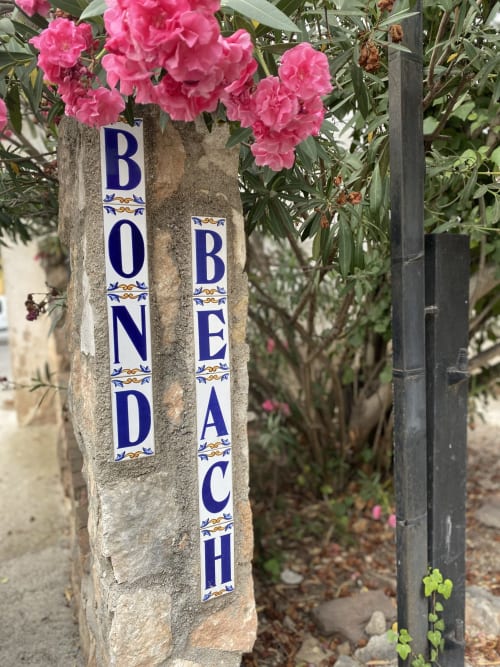 Flores rosas floreciendo sobre el cartel decorativo 'Bondeach' en BondBeach Village, Altafulla, España