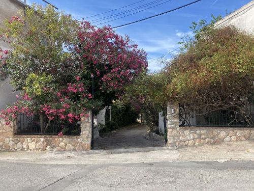 Vibrantes flores de buganvilia magenta enmarcan la entrada a BondBeach Village en Altafulla, con muros de piedra y sendero