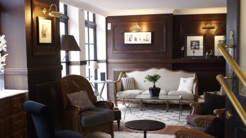Élégant salon du Be Hotel Le Touquet avec boiseries foncées, canapé crème, fauteuils et luminaires en laiton