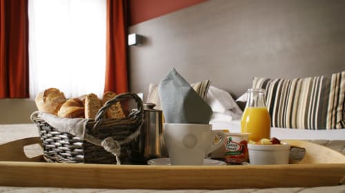 Plateau de petit-déjeuner dans une chambre de l'hôtel Le Touquet avec croissants, jus et service de café sur table en bois