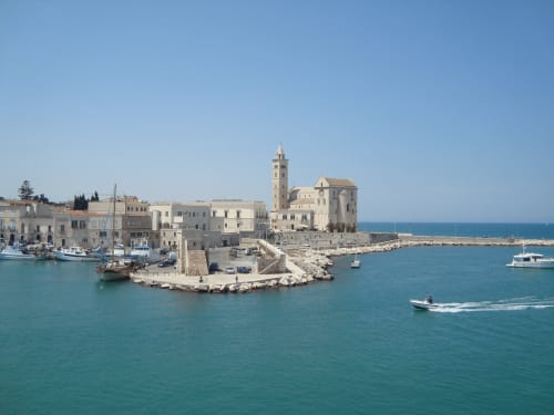 Suggestiva vista del lungomare di Bari con chiesa storica e barche nelle acque turchesi del Mediterraneo, Italia