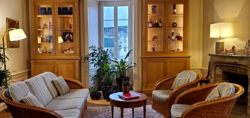Élégant salon du Logis des Tourelles à Cognac avec fauteuils rayés, vitrines en bois et vue sur la campagne