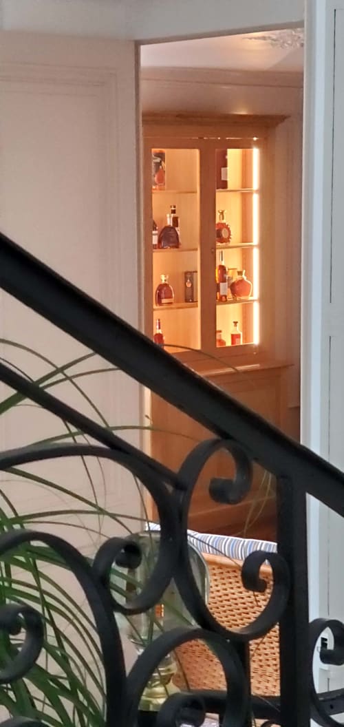 Étagères illuminées avec des bouteilles de cognac vues depuis l'escalier du Logis des Tourelles, Cognac