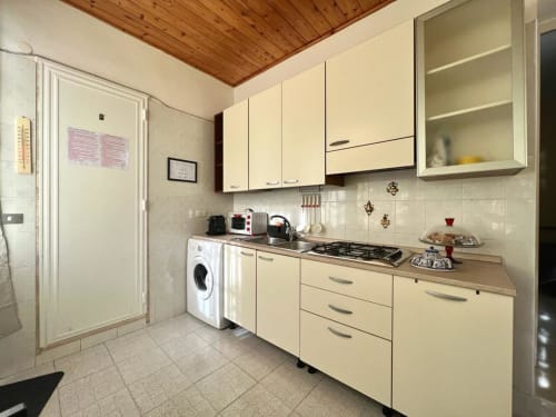 Cucina color crema con soffitto in legno, cucina a gas, lavatrice e rivestimento in piastrelle bianche a Villa Newhouse a Bari