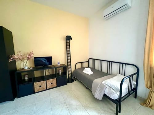 Camera moderna alla villa Newhouse di Bari con letto in metallo nero, scrivania con TV e aria condizionata