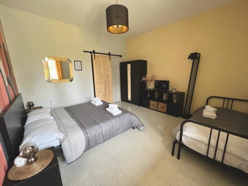 Ampia camera da letto della villa Newhouse Bari con due letti, arredamento nero, pareti gialle e servizi moderni