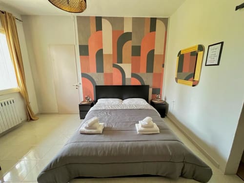 Camera da letto di villa Newhouse a Bari con testiera geometrica moderna, letto nero, biancheria crema e pareti giallo-verdi