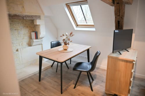 Espace de travail loft moderne à la Villa République Normandie avec bureau en bois, chaises noires et puits de lumière dans l'appartement de Caen