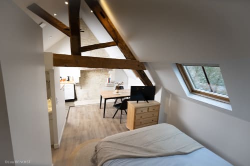 Chambre mansardée moderne à la Villa République Normandie à Caen avec poutres apparentes, lit, bureau et fenêtre de toit