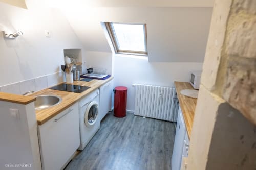Petite cuisine de l'Appartement Marianne à Villa République Normandie, Caen, avec placards blancs, plan de travail en bois et lave-linge