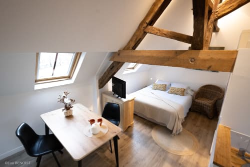 Chambre mansardée à la Villa République Normandie à Caen avec poutres apparentes, lucarne, lit, bureau et fauteuil en rotin