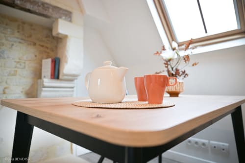Ambiance cosy avec théière blanche et tasses orange sur table en bois à la Villa République Normandie B&B à Caen