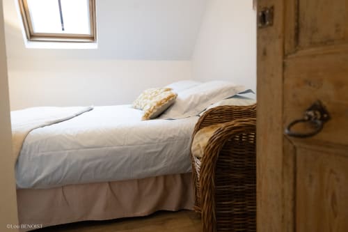 Chambre cosy de la Villa République Normandie B&B à Caen avec draps blancs, coussin doré, panier en osier, porte en bois et