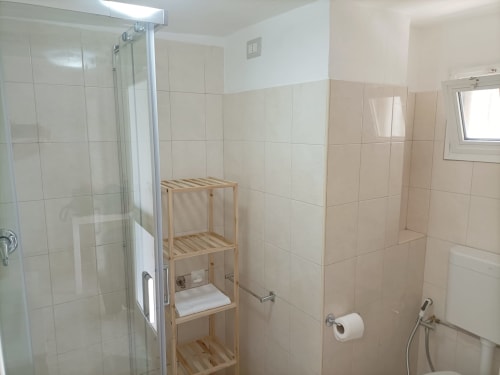 Bagno moderno dell'appartamento Newhouse a Bari con doccia, scaffali in legno e piastrelle bianche