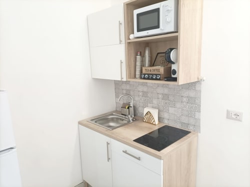Angolo cottura compatto dell'appartamento Newhouse a Bari con microonde, lavello, piano cottura e mobiletti contenitori