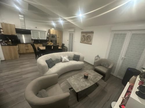 Séjour ouvert et contemporain au Gîte du Miroir à Domérat avec canapé crème arrondi, cuisine dînatoire