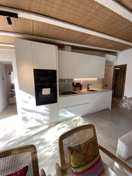 Cocina blanca moderna con electrodomésticos negros e isla central en la villa BondBeach Village de Altafulla, España