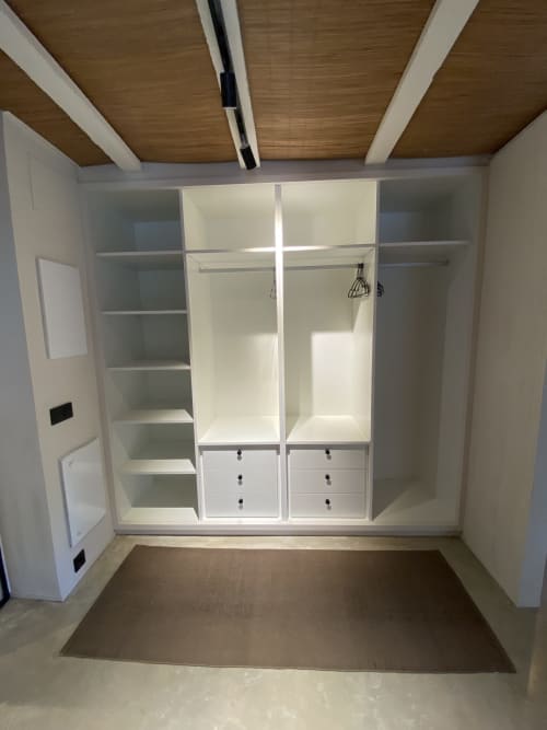 Elegante vestidor con estanterías blancas empotradas, cajones y barras de colgar en la villa BondBeach Village de Altafulla