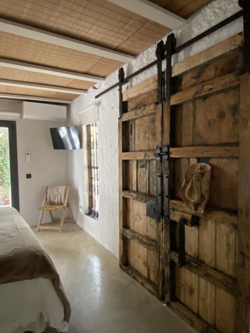 Dormitorio de villa moderna con puertas de granero rústicas y vigas de madera vista en BondBeach Village, Altafulla