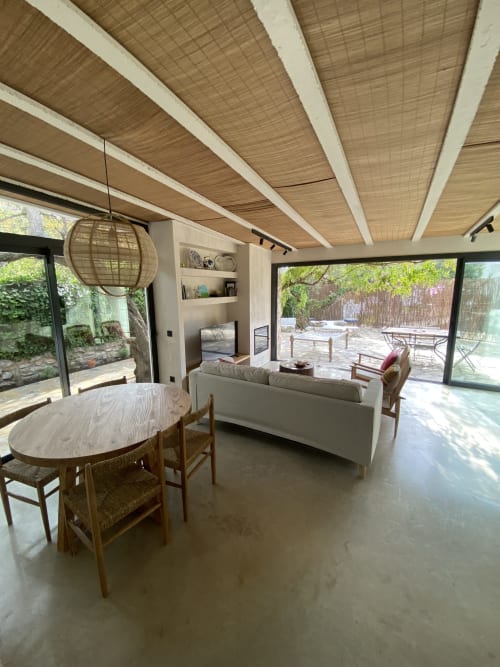 Zona de estar moderna de la villa en BondBeach Village con mesa de comedor, asientos y vistas al jardín a través de puertas de cristal