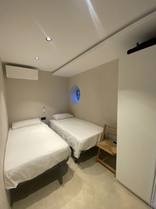 Dormitorio doble en villa BondBeach Village en Altafulla con camas blancas, luces de techo y ventana portilla azul