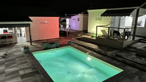 Piscine illuminée du Kaz A Bibi BnB la nuit à Sainte-Rose, Guadeloupe avec eau turquoise et bungalows colorés