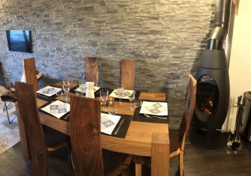 Élégante salle à manger d'un appartement de luxe à Courchevel avec table en bois, mur en pierre, cheminée et vue sur les montagnes
