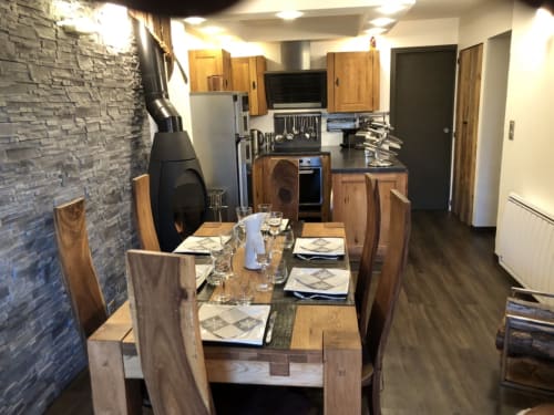 Cuisine-salle à manger moderne dans un appartement 4 étoiles à Courchevel avec table en bois, cuisinière et mur d'accent en pierre contemporain